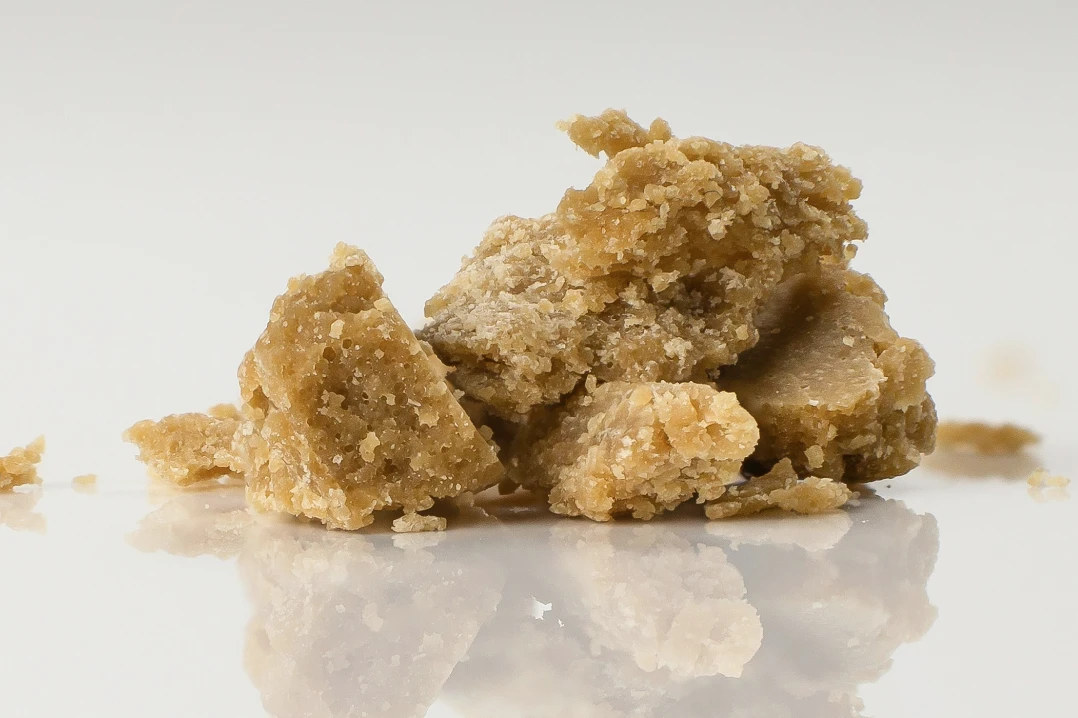 A pile of THCA concentrate hash with a rich, granular texture, showcasing its potency and purity.