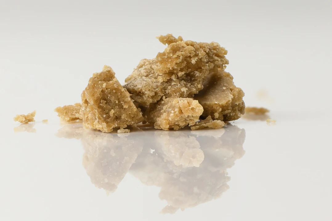 Close-up image of THCA rosin, showcasing its golden, glossy texture and rich, sticky consistency, presented on a dab tool with a clean background, highlighting the purity and craftsmanship of this cannabis concentrate.